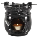 Black marble-patterned oil burner with a lit tealight candle on a white background