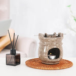 Aroma lamp with a small candle and diffuser on a woven coaster.