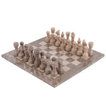 A marble chess set with pieces arranged on the board, including kings, queens, knights, bishops, rooks, and pawns. The set is displayed on a checkered patterned surface.