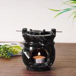Black marble oil burner with a lit candle on a wooden surface