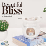 White marble oil burner with a lit candle on books, surrounded by decorative items, with text 'Beautiful Bliss' on a white background.
