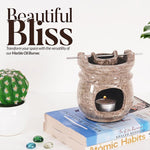 Marble oil burner on books with a cactus and decorative stones, featuring text 'Beautiful Bliss'.