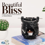 Black marble oil burner with a lit candle on books, surrounded by decorative items, with 'Beautiful Bliss' text.