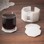 A set of marble star-shaped coasters with one holder, displayed on a wooden surface, with one coaster being used to hold a glass of liquid.